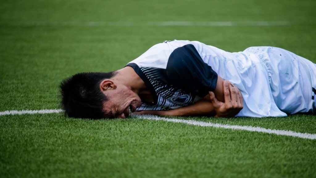Person laying on the soccer field depicting what happens if a concussion goes untreated and why functional evaluation identifies deficits a normal scan does not